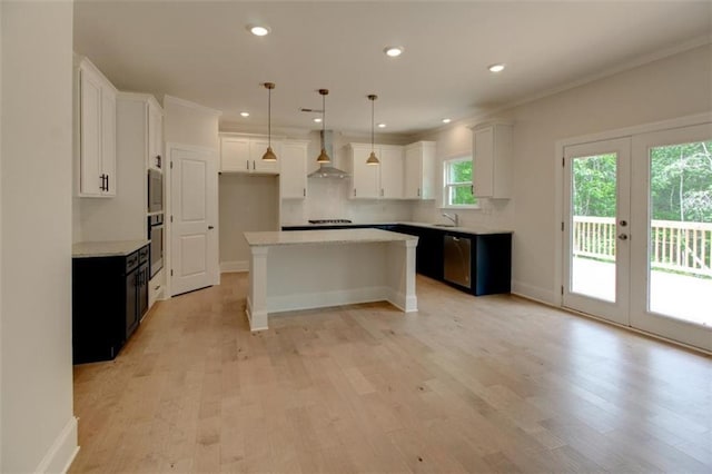 kitchen featuring stainless steel appliances, white cabinets, light wood-style flooring, and wall chimney exhaust hood