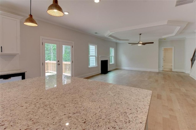 kitchen featuring light wood-style flooring, a fireplace, visible vents, white cabinets, and a tray ceiling