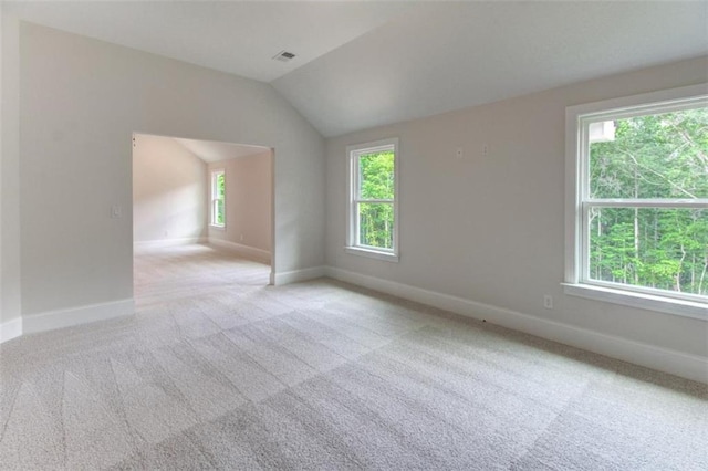 unfurnished room featuring carpet, visible vents, vaulted ceiling, and baseboards