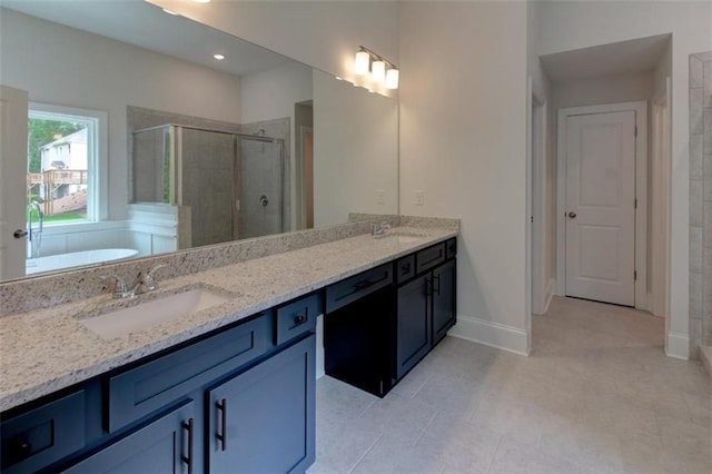 bathroom with double vanity, a stall shower, a sink, and baseboards