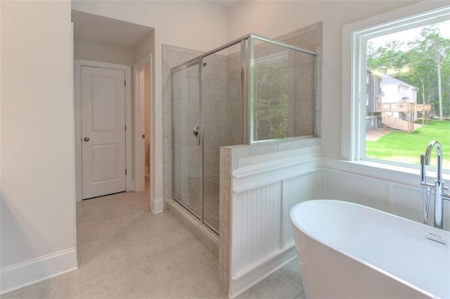 bathroom with a freestanding bath, a shower stall, and tile patterned floors