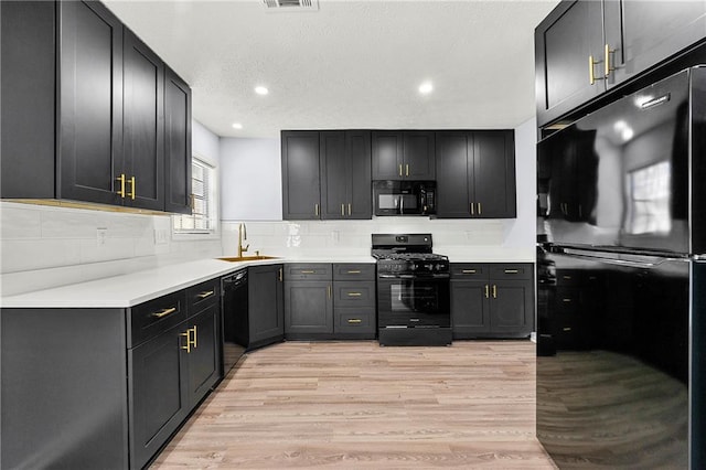 kitchen featuring light hardwood / wood-style floors, black appliances, tasteful backsplash, and sink