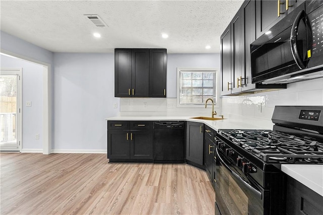 kitchen with sink, a textured ceiling, light hardwood / wood-style floors, backsplash, and black appliances