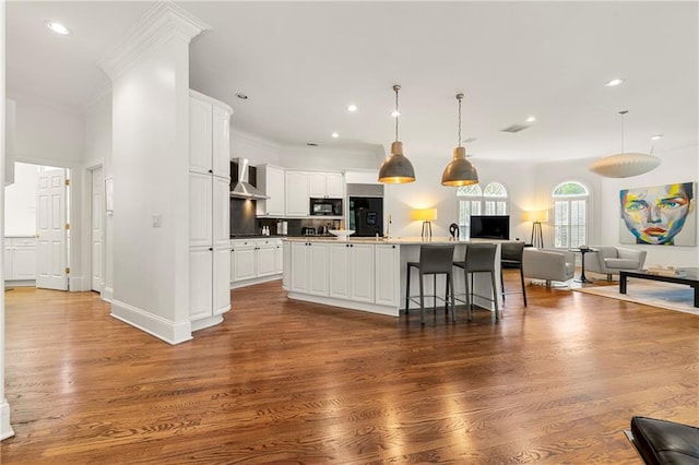 kitchen with wall chimney exhaust hood, white cabinetry, a center island with sink, and dark hardwood / wood-style flooring