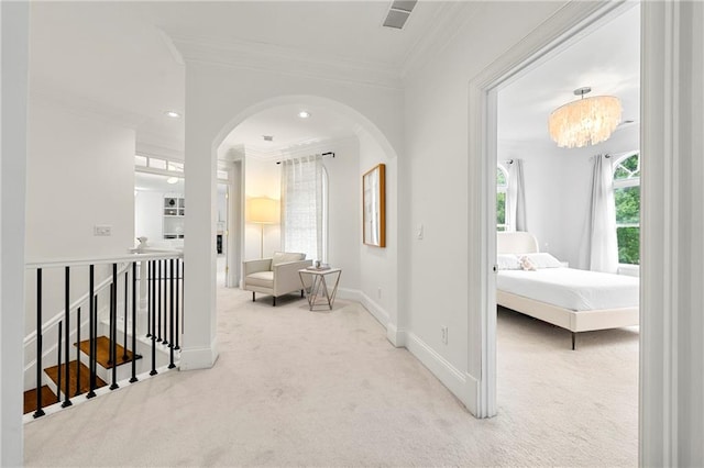 hallway featuring carpet floors, ornamental molding, and a notable chandelier