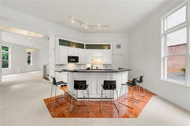 kitchen with ornamental molding, white cabinets, decorative backsplash, and a breakfast bar area