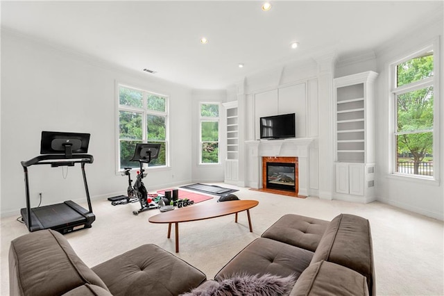 living room with light carpet, ornamental molding, a high end fireplace, and a healthy amount of sunlight