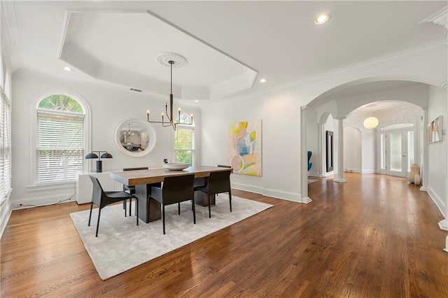 dining space featuring a tray ceiling, light wood-type flooring, a chandelier, and a wealth of natural light