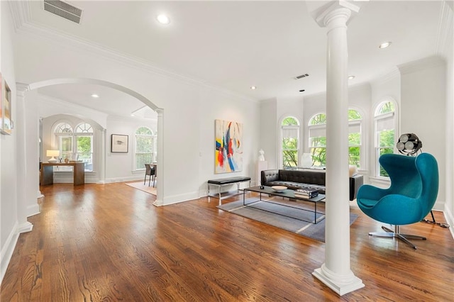 living room featuring decorative columns, hardwood / wood-style flooring, and crown molding