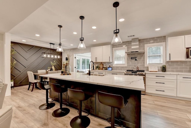 5441 E Main St, Flowery Branch, GA 30542 - kitchen featuring stainless steel appliances, wall chimney range hood, white cabinets, light stone counters, and backsplash
