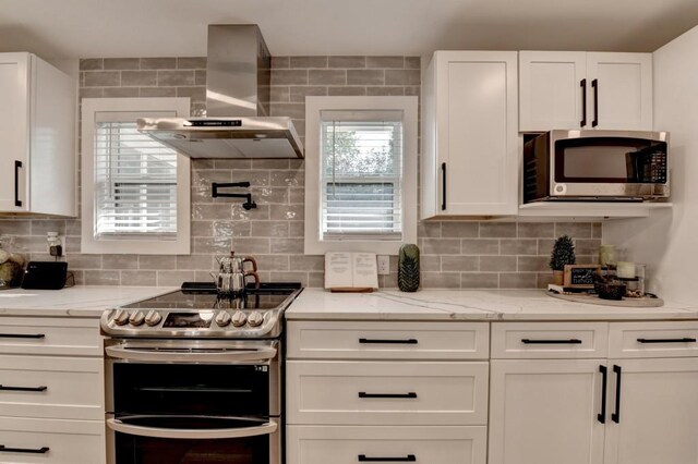 5441 E Main St, Flowery Branch, GA 30542 - kitchen featuring appliances with stainless steel finishes, wall chimney range hood, white cabinets, tasteful backsplash, and light wood finished floors