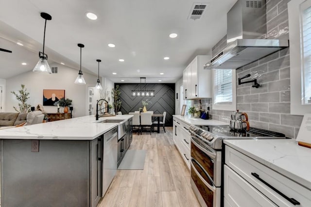 5441 E Main St, Flowery Branch, GA 30542 - kitchen with wall chimney exhaust hood, appliances with stainless steel finishes, light wood-type flooring, recessed lighting, and white cabinets
