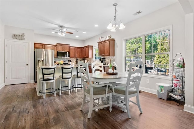 dining room with dark hardwood / wood-style flooring and ceiling fan with notable chandelier