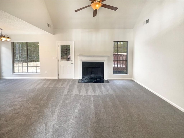 unfurnished living room featuring dark colored carpet, ceiling fan with notable chandelier, and high vaulted ceiling