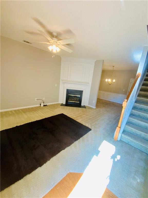 unfurnished living room with ceiling fan with notable chandelier and light hardwood / wood-style flooring