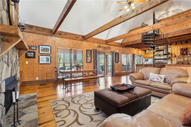 living area with wood walls, plenty of natural light, hardwood / wood-style floors, and beamed ceiling