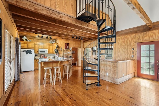 kitchen featuring white appliances, wood walls, light wood-style flooring, and beam ceiling