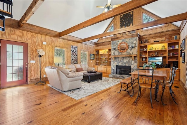 living area with wood walls, a fireplace, beam ceiling, and hardwood / wood-style floors