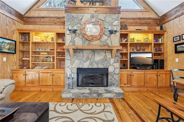 living room with lofted ceiling with skylight, a fireplace, wood walls, and wood finished floors