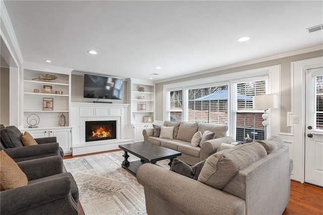 living room with hardwood / wood-style flooring, a fireplace, and ornamental molding