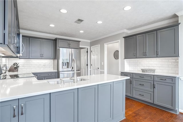 kitchen featuring stainless steel refrigerator with ice dispenser, gray cabinets, dark wood-type flooring, and stove