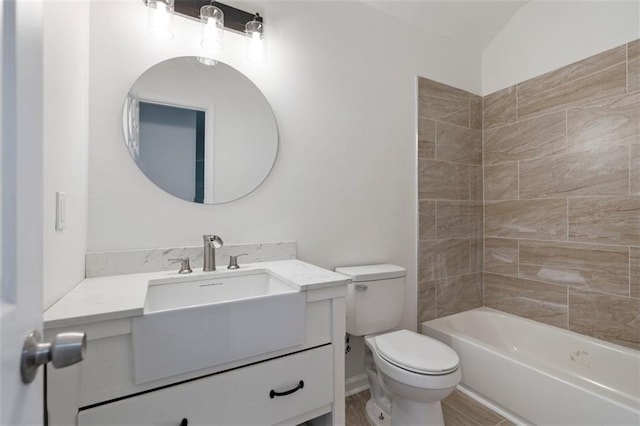 full bathroom featuring vanity, tiled shower / bath, and toilet