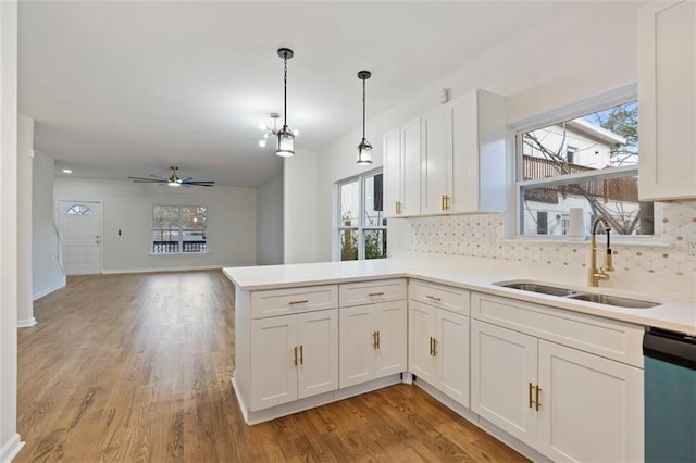 kitchen with dishwashing machine, sink, white cabinetry, decorative light fixtures, and kitchen peninsula