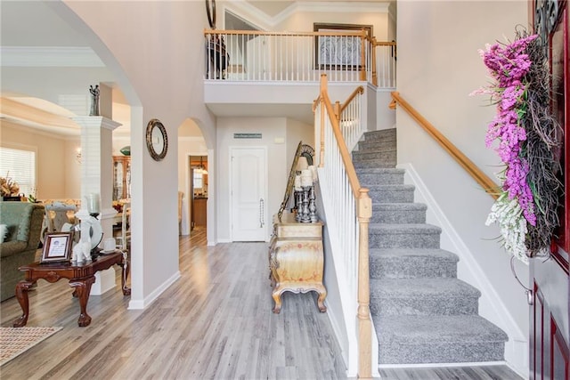 3258 Kessock Ridge Trl, Snellville, GA 30039 - entrance foyer featuring arched walkways, a high ceiling, stairway, wood finished floors, and crown molding