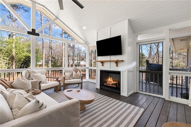 sunroom / solarium featuring a glass covered fireplace, vaulted ceiling, wood ceiling, and a ceiling fan