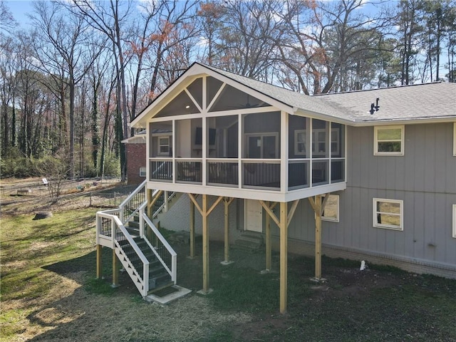 back of house featuring roof with shingles, stairs, and a sunroom