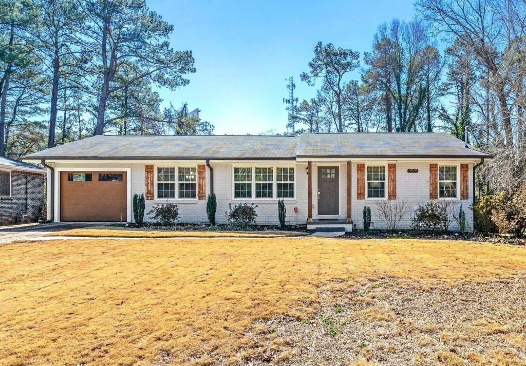 ranch-style house featuring a front lawn, an attached garage, brick siding, and driveway
