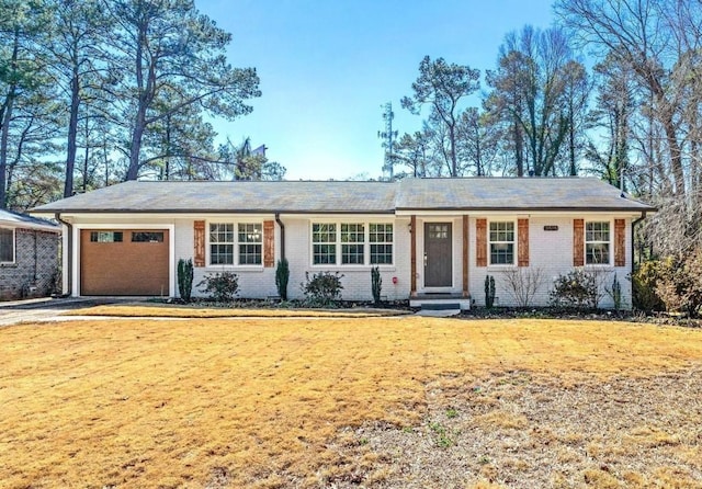 ranch-style house featuring a front lawn, an attached garage, brick siding, and driveway