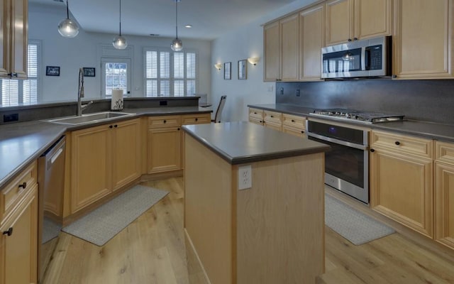 kitchen with sink, pendant lighting, stainless steel appliances, and a center island