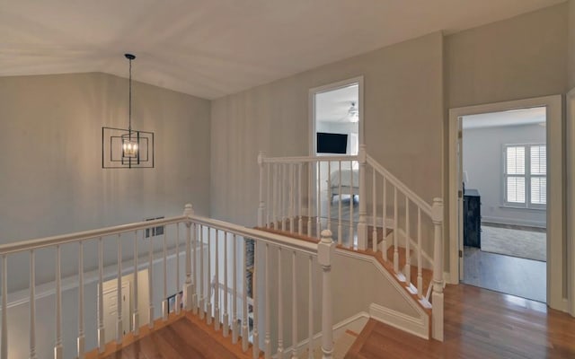 stairs with lofted ceiling, hardwood / wood-style flooring, and a notable chandelier