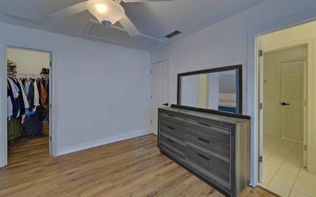 bedroom with ceiling fan, a spacious closet, a closet, and light wood-type flooring