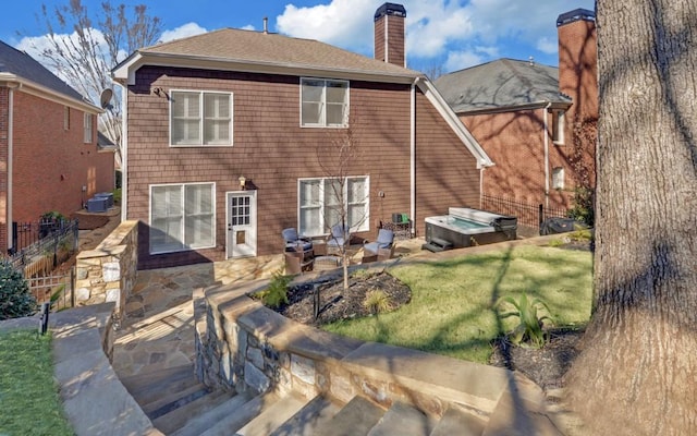 rear view of property featuring a jacuzzi, a yard, and a patio