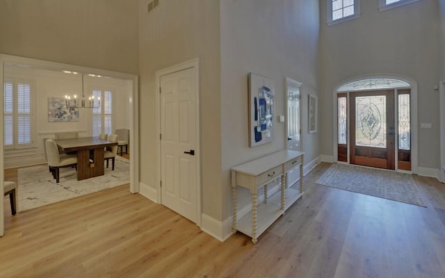 foyer entrance with a high ceiling, hardwood / wood-style floors, and a chandelier