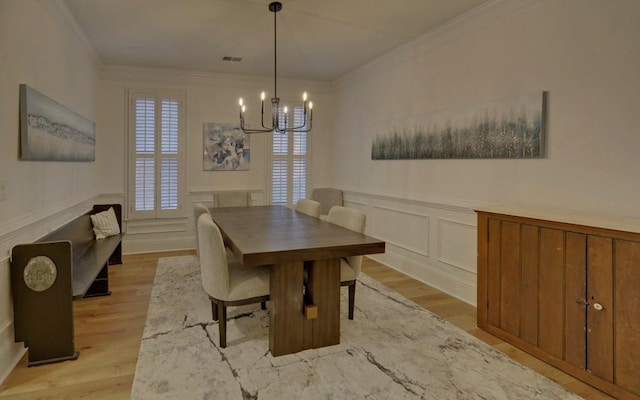 dining space with crown molding, a chandelier, and light wood-type flooring