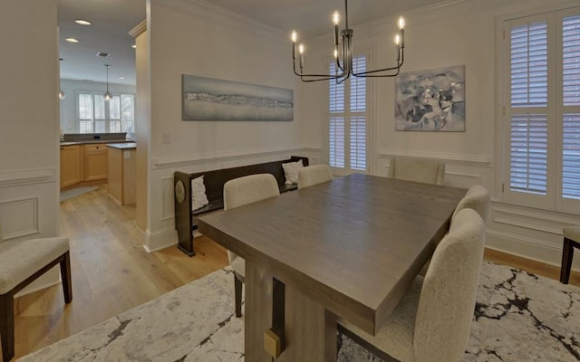 dining space with an inviting chandelier, crown molding, and light hardwood / wood-style flooring