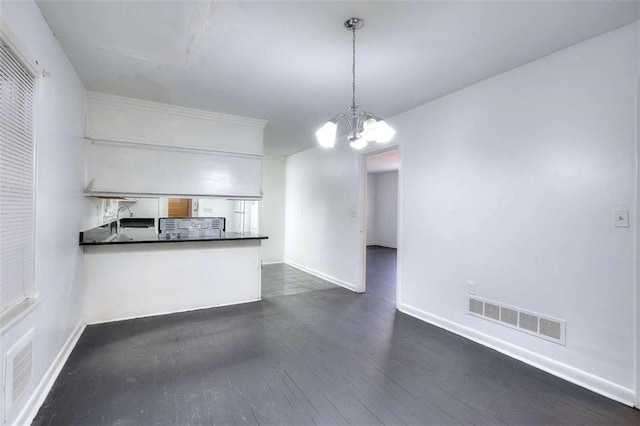 707 E Spring St E, Monroe, GA 30655 - kitchen featuring dark countertops, a chandelier, a peninsula, dark wood-style flooring, and baseboards