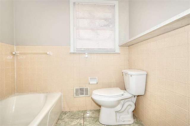 707 E Spring St E, Monroe, GA 30655 - full bathroom with tile walls, toilet, a bathtub, tile patterned floors, and a wainscoted wall