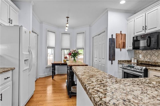 137 Oakton S, Eatonton, GA 31024 - kitchen with light wood finished floors, white cabinetry, white refrigerator with ice dispenser, stainless steel range with electric stovetop, and black microwave