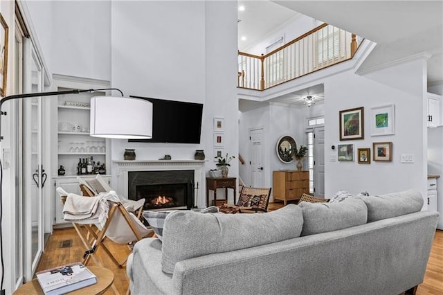 137 Oakton S, Eatonton, GA 31024 - living room with light wood-style flooring, a high ceiling, a warm lit fireplace, and ceiling fan