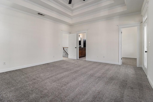 carpeted spare room featuring visible vents, baseboards, a tray ceiling, ornamental molding, and a ceiling fan