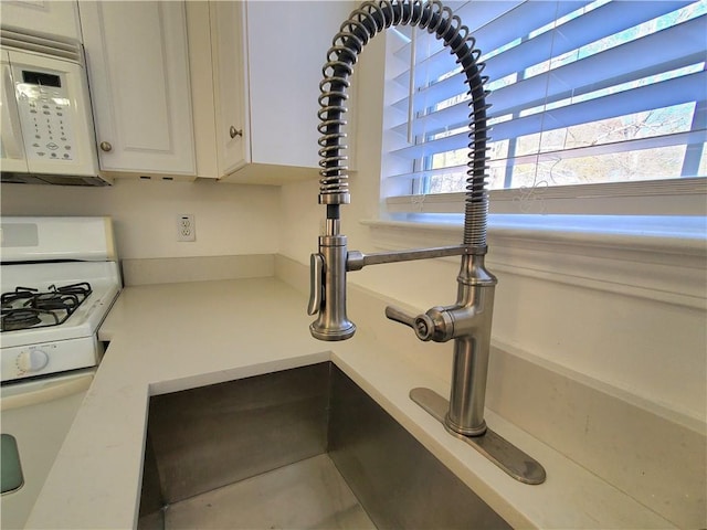 interior details featuring white cabinets, white appliances, and sink