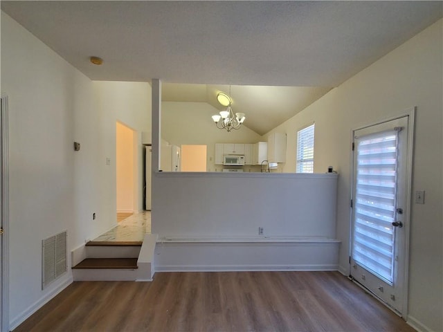 interior space with light hardwood / wood-style floors, lofted ceiling, and a chandelier