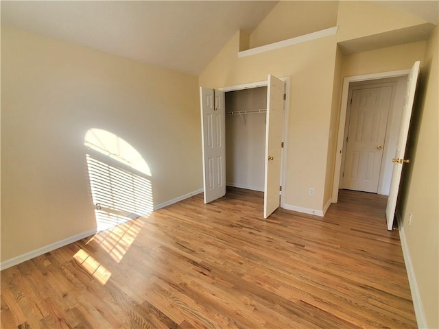 unfurnished bedroom featuring a closet, light hardwood / wood-style flooring, and high vaulted ceiling