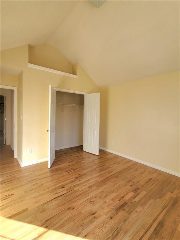 unfurnished bedroom with a closet, vaulted ceiling, and light hardwood / wood-style flooring