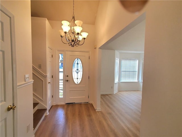 foyer entrance featuring hardwood / wood-style floors, high vaulted ceiling, a healthy amount of sunlight, and a notable chandelier