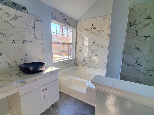 bathroom with vanity, a tub to relax in, tile walls, and lofted ceiling